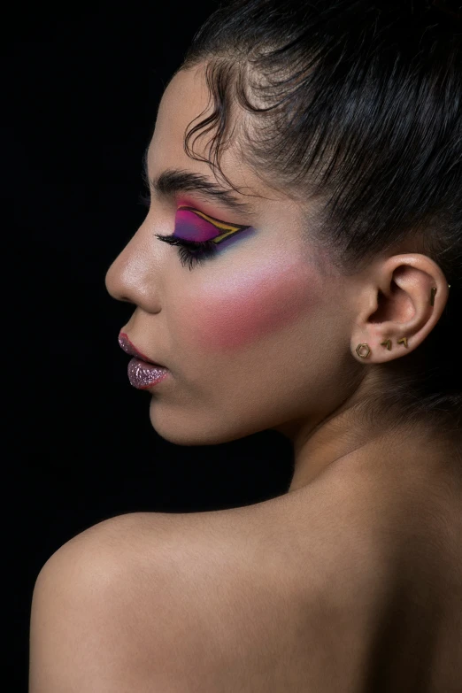 a woman with black hair and pink makeup looks down while her upper half is down