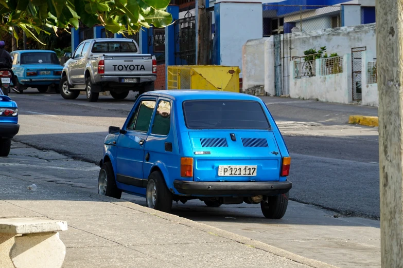 a small blue car on the side of a road