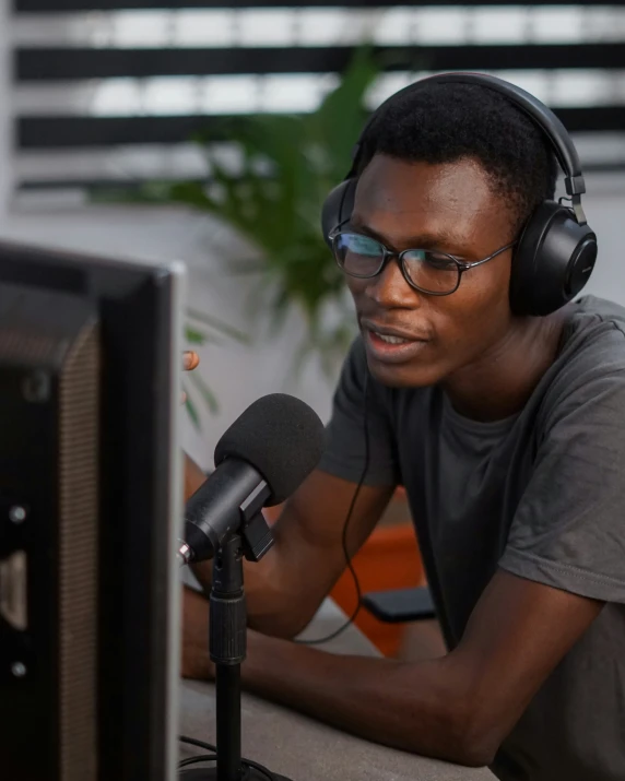 a man sitting next to a computer wearing headphones