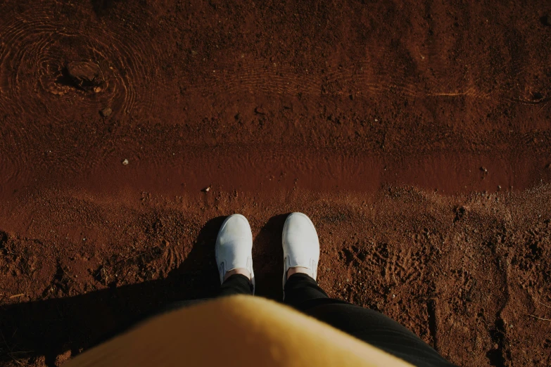 the view of a person's feet and shoe on a dirt ground