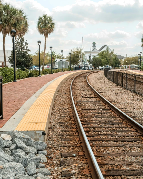 some tracks at a railroad station surrounded by palm trees