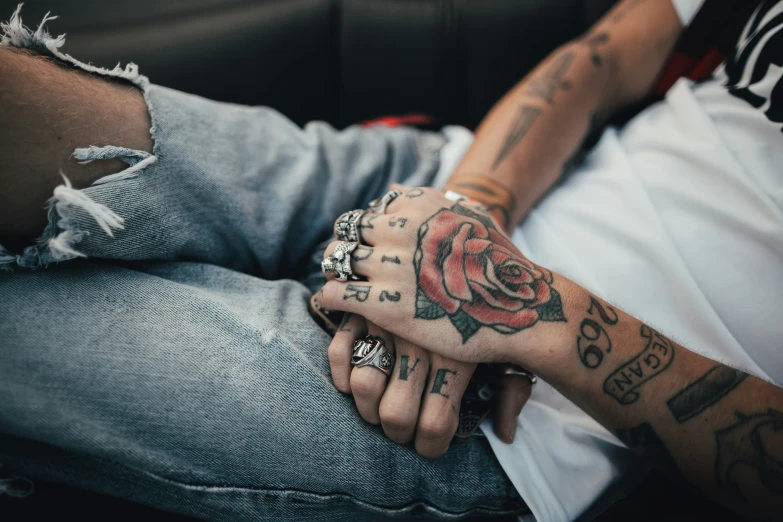 a couple sitting together holding hands and tattoos