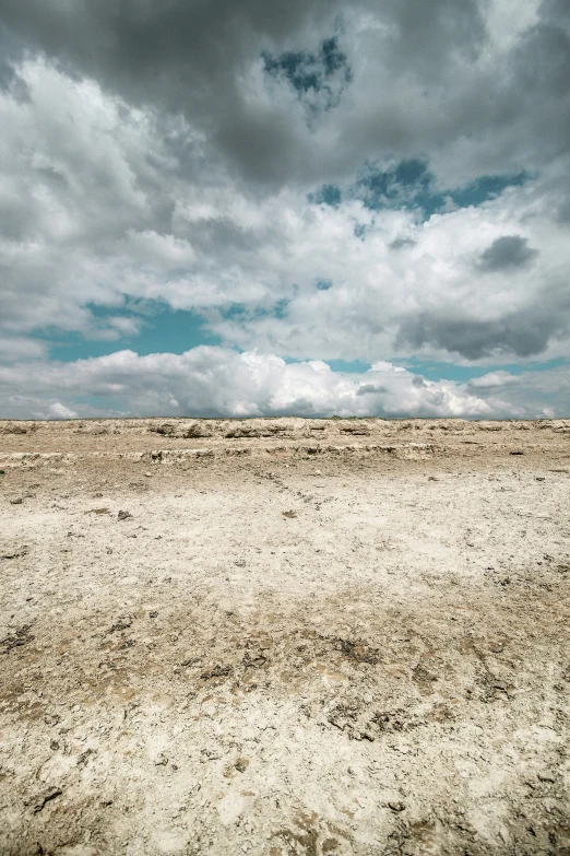 a person on horseback galloping through the desert under cloudy skies