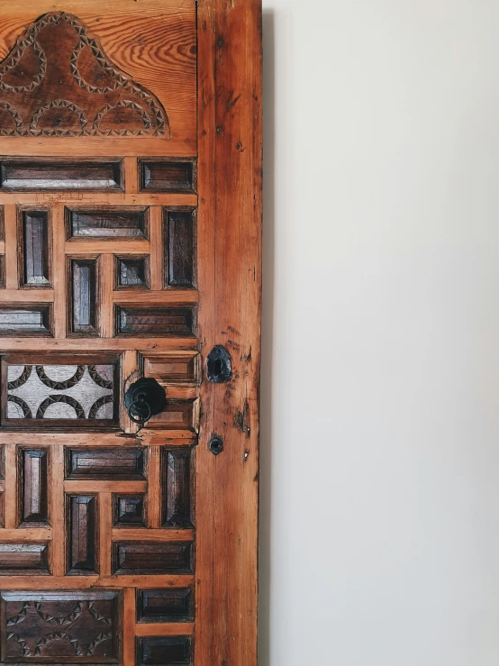 a wooden door on a white wall with carvings in it