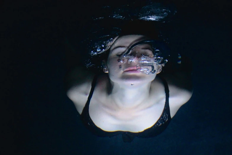 a woman with her eyes closed swimming in the dark