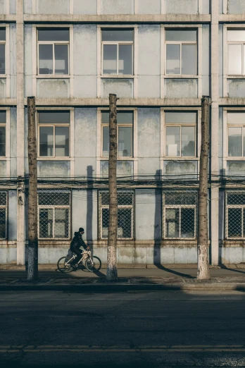 a person on a bike rides by an old building