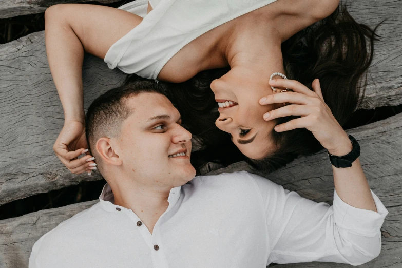 a couple laying on a wooden bench holding each other's hands