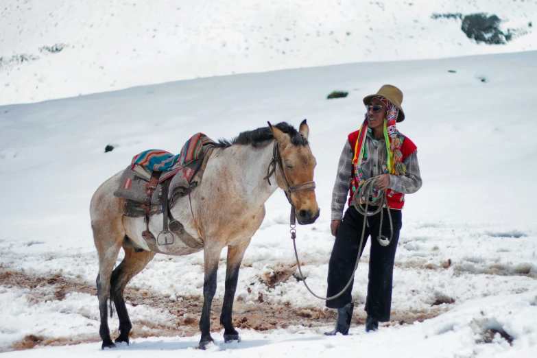 a man stands next to his horse in the snow