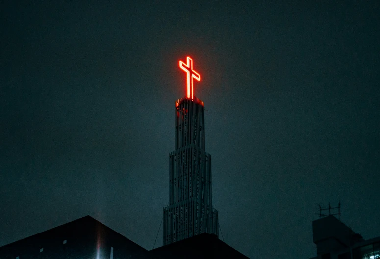 a large neon cross on top of a building