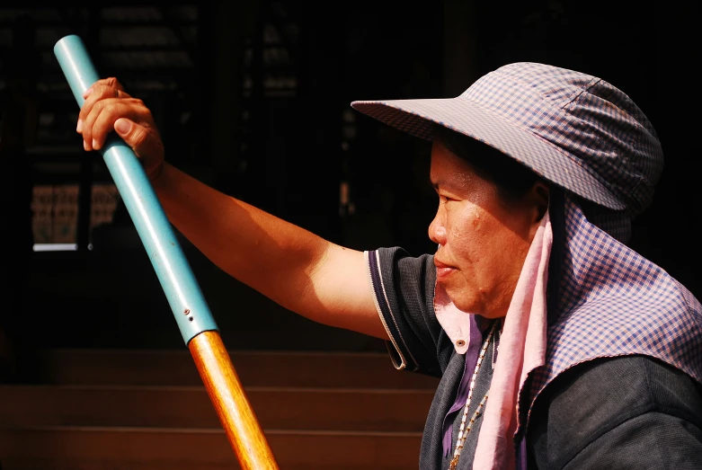 a woman with a hat and scarf holding up a large pole