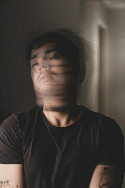 a man with arm tattoos has his face obscured by blinds