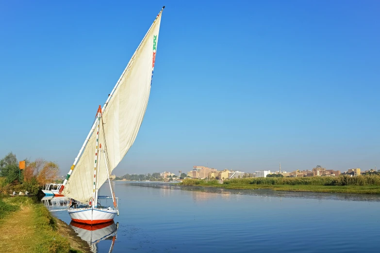 a sailboat on the water near a bank