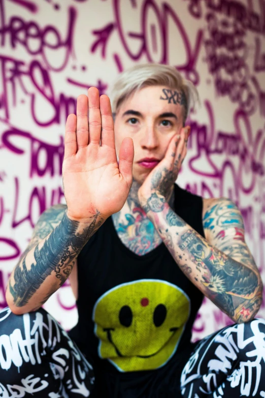 a man with tattoos sitting in front of graffiti covered walls