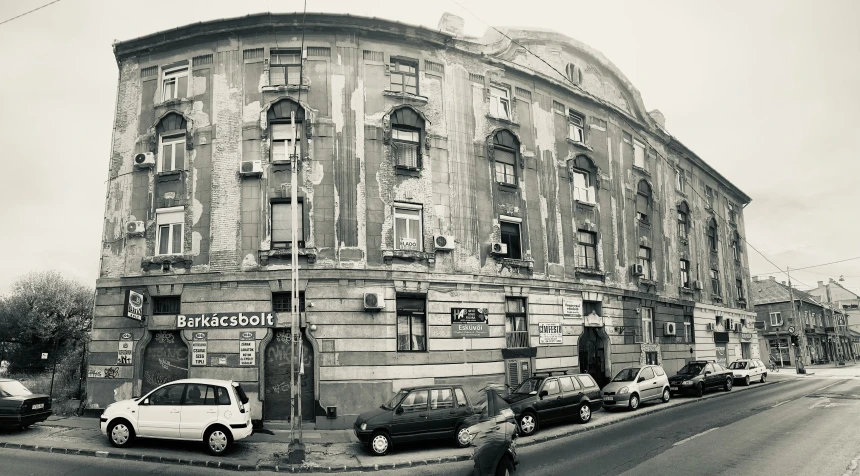 a black and white image of a building with cars parked next to it