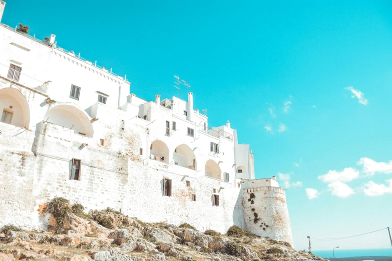 white and stucco castle with tall buildings with red flowers