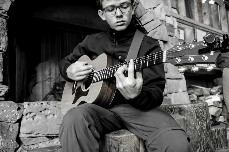 a man sits on a bench while playing a guitar