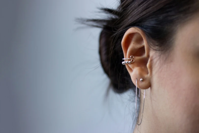 a woman's ear with multiple pairs of silver ear rings