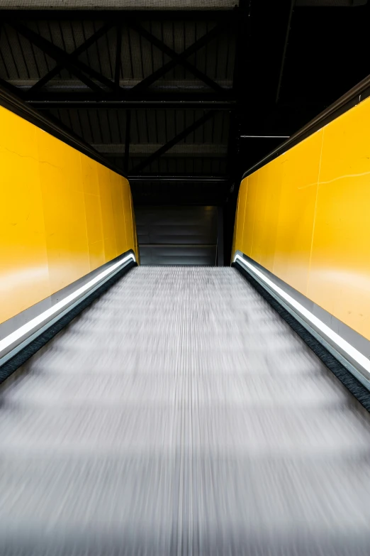 an empty moving yellow escalator in a train station