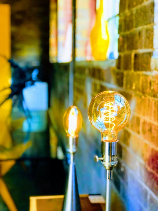 two glass lights with long stem are next to a brick wall