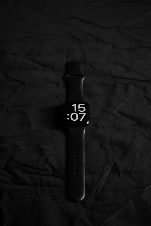 an analog watch with a black strap and black numbers on a black cloth