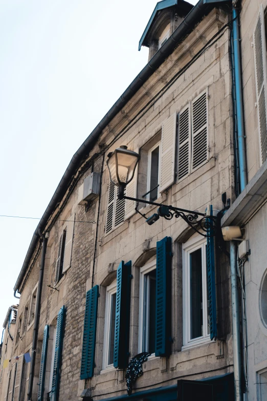 a building with many windows and shutters and a street light