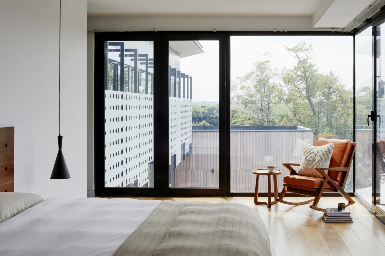 a bedroom with a white bed, brown chair and a glass sliding door