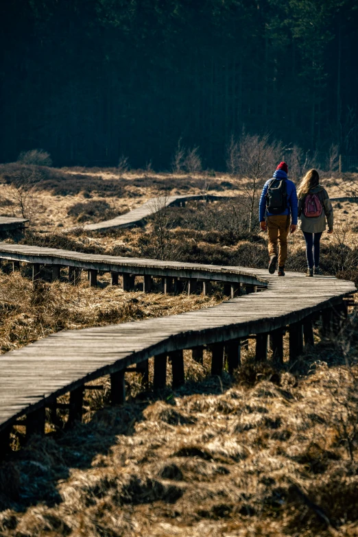 two people walking up an old wooden bridge