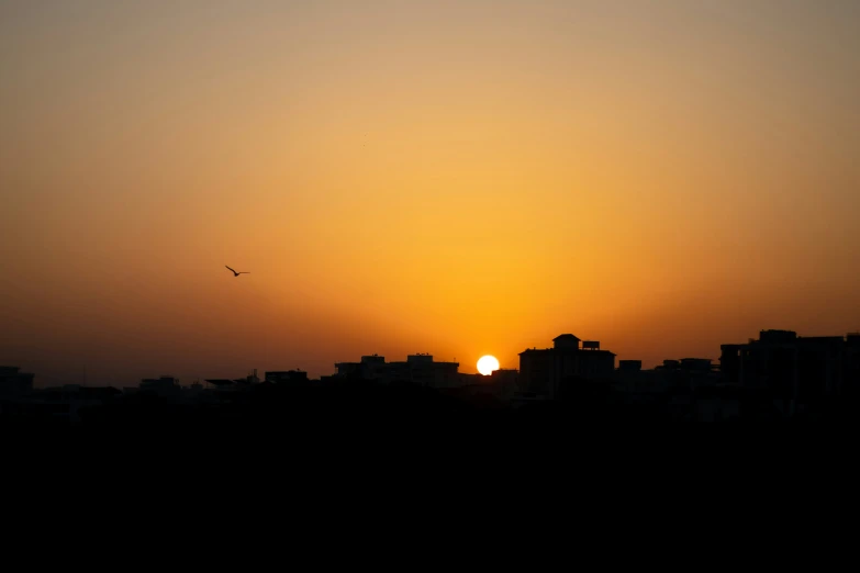 the sun setting behind buildings on the horizon