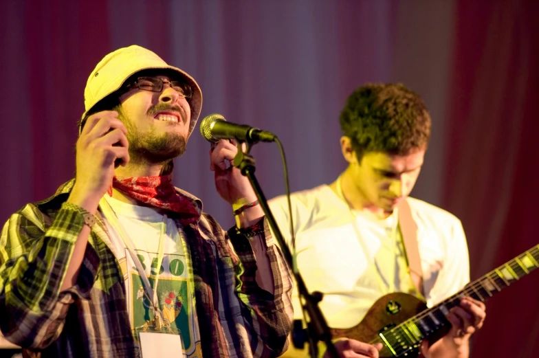 a man standing in front of a microphone while holding an electric guitar