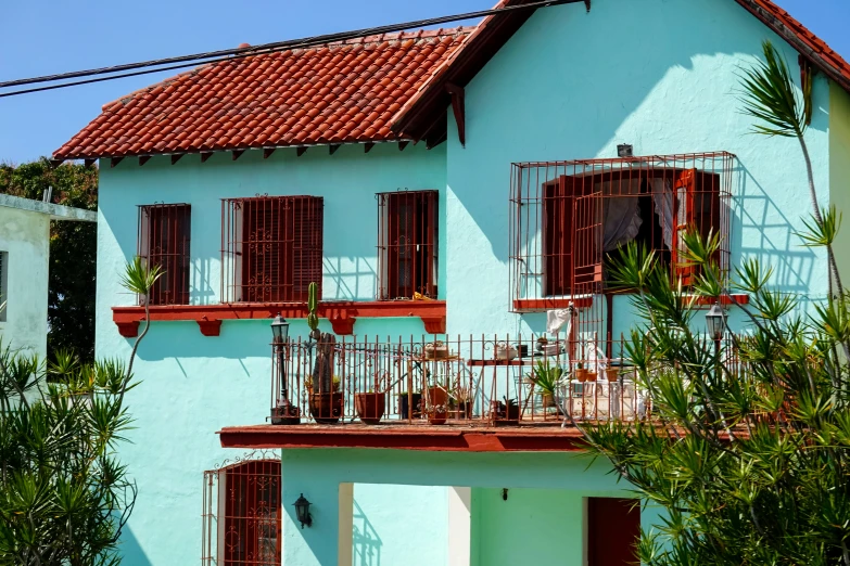 a blue house with red roof and balconies