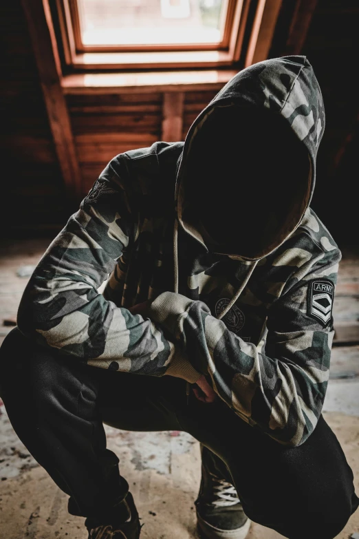 a person kneeling down wearing a hoodie and pants