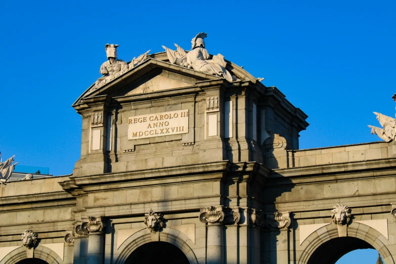 the top of a large gray building with statues on it