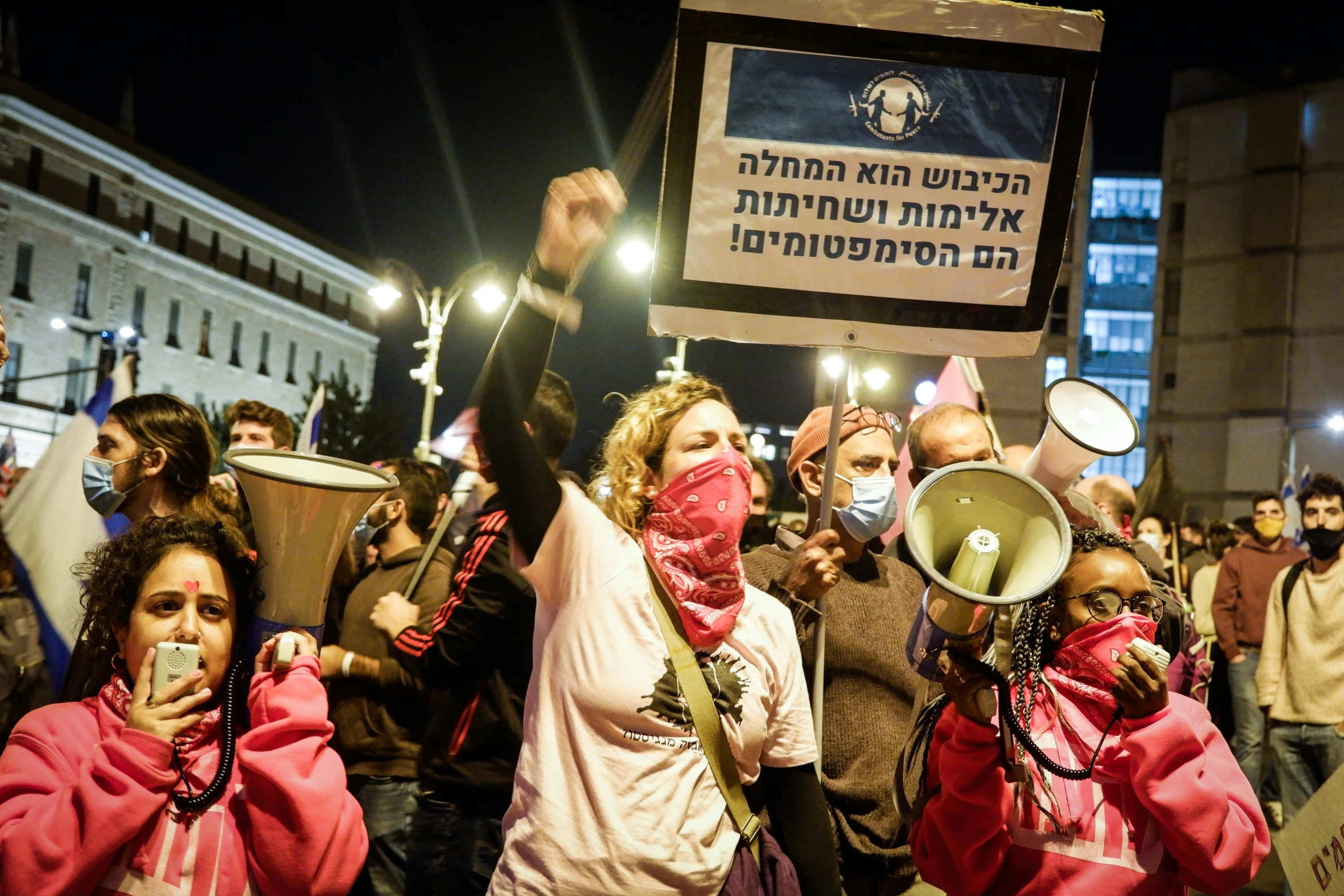 the protesters with their masks are holding candles and signs