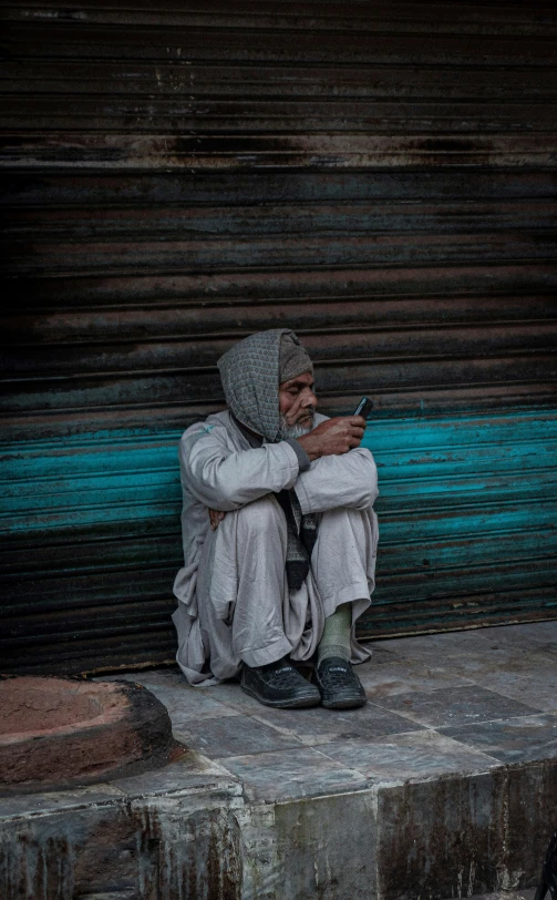 a man sits on steps with a cellphone