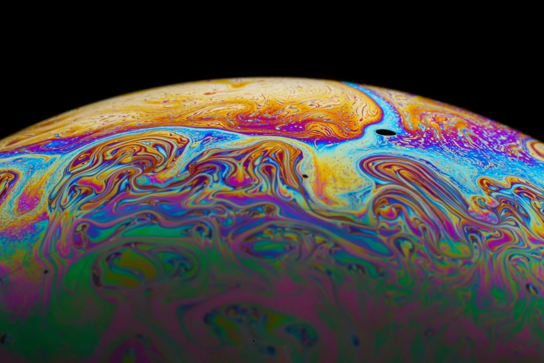 a closeup of an orange, blue, green, and yellow substance with swirls