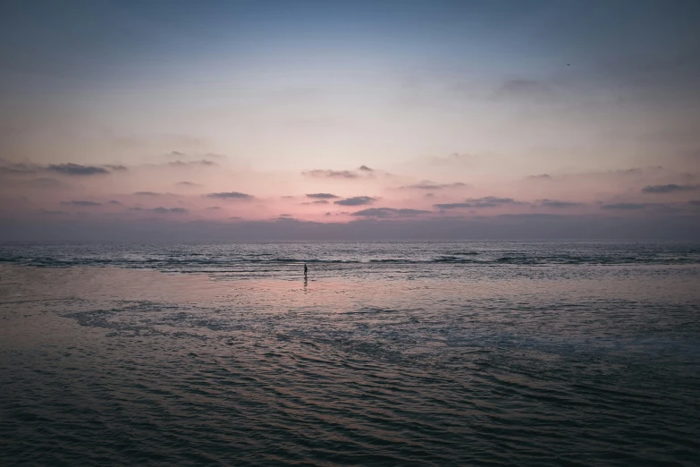 two people stand on the beach in front of the ocean