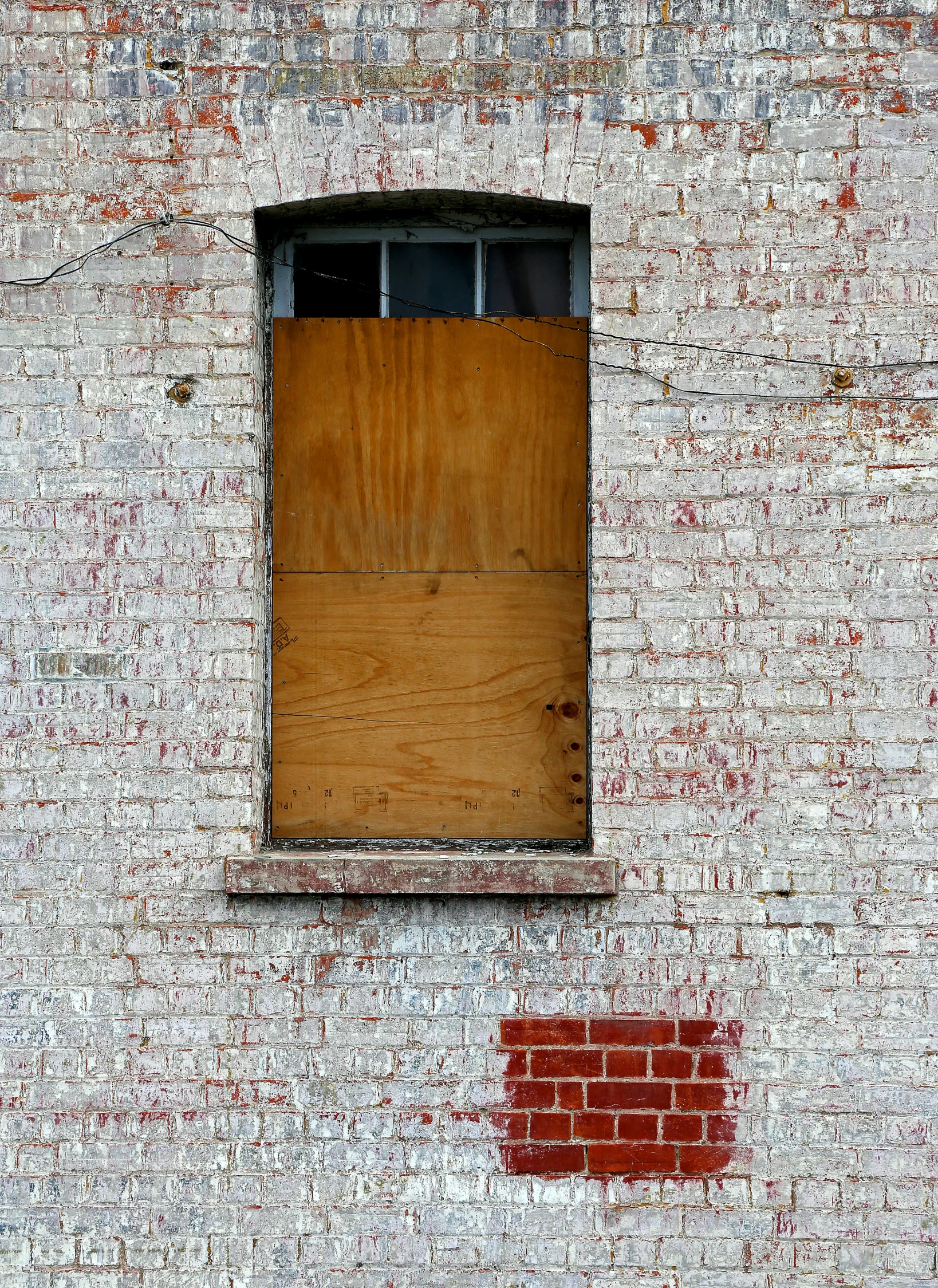 a boarded window and boarded door on a weathered brick building