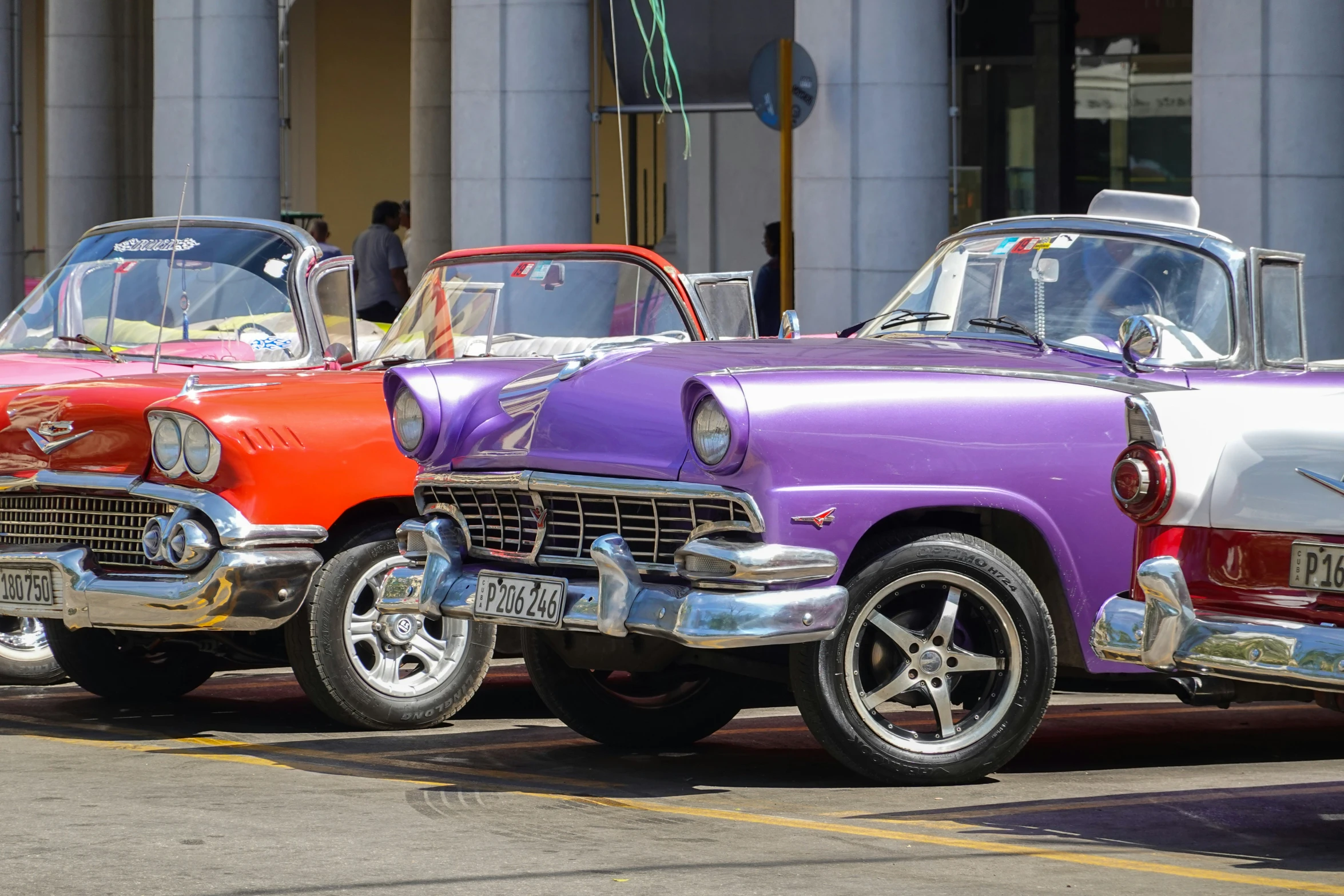 three old - fashioned cars parked in line on the side of a street