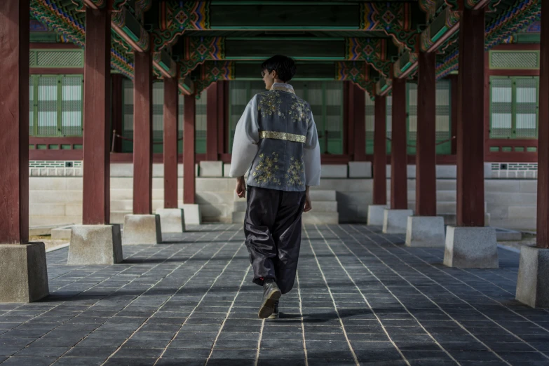 an asian man walks in an oriental hallway