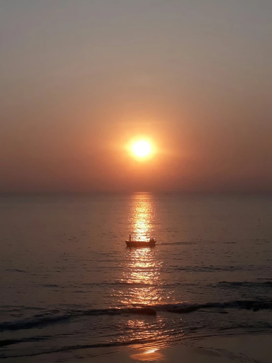 a small boat is out on the ocean at sunset