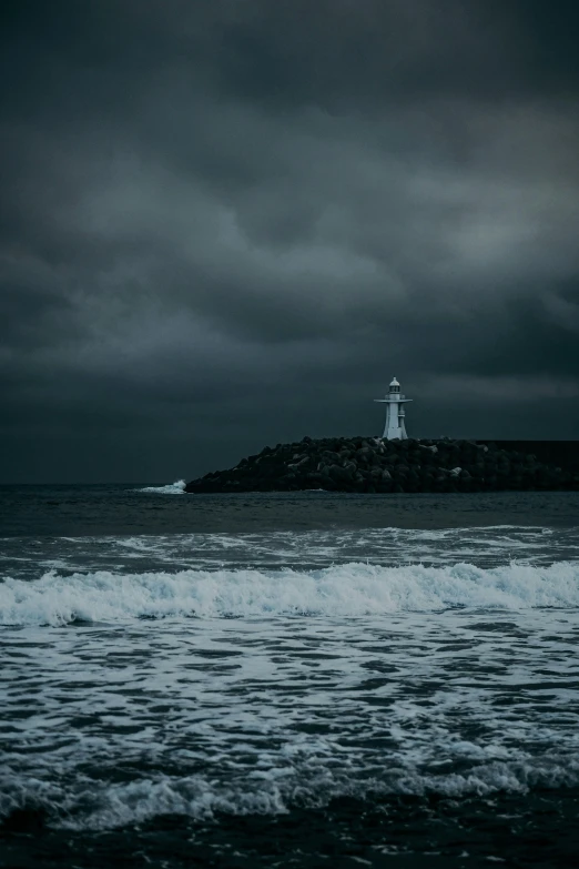 a lighthouse on a island at the end of a stormy sea