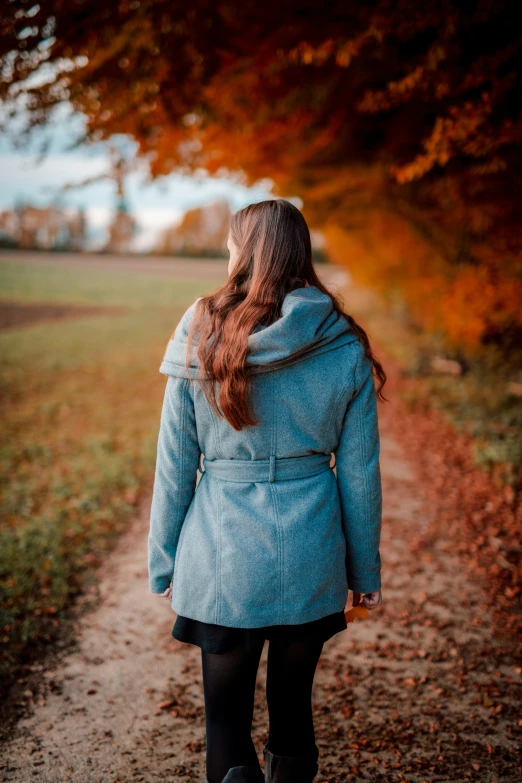 a woman wearing a jacket standing in front of trees