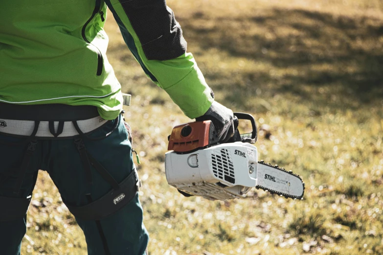 a man holding a chainsaw in a grassy area