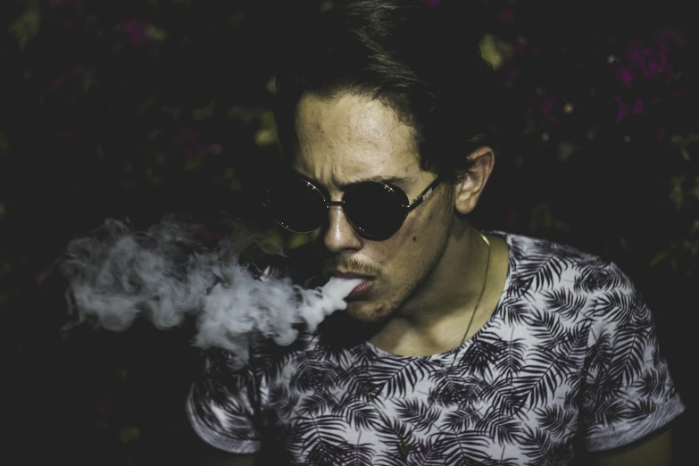 the man wearing sunglasses smokes an electronic cigarette