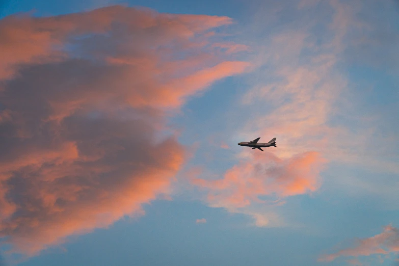 an airplane flying through a blue sky with orange clouds