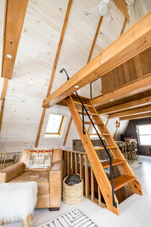 a loft with a loft type stair case that is made of wood and has a loft like area with high ceilings