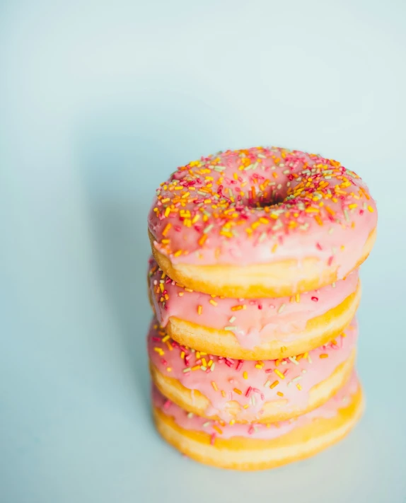 a stack of donuts covered in pink frosting and sprinkles