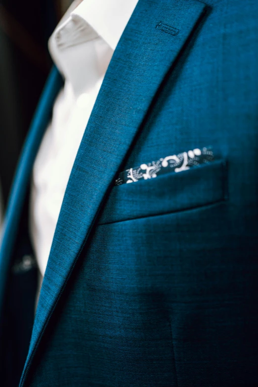 a closeup view of a person in a blue suit with metal lapels