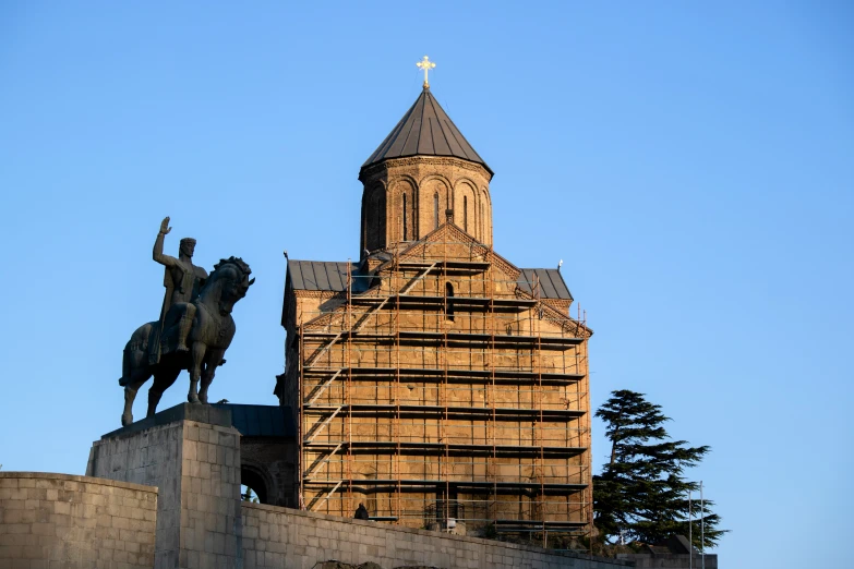 the statue is sitting beside a tower and the building