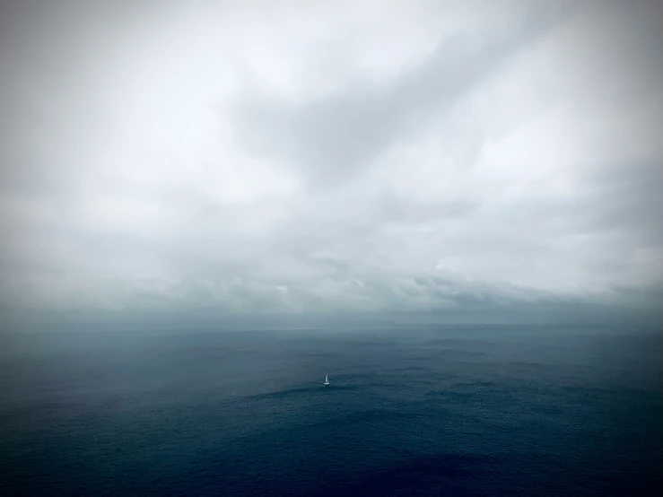 a small boat sailing on the ocean under a cloudy sky